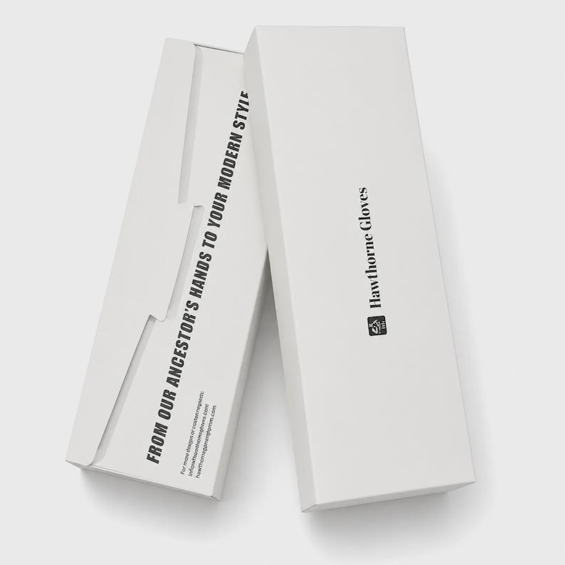 Op de afbeelding: Twee witte rechthoekige kartonnen dozen voor Hawthorne Gloves. De bovenste doos bevat de merknaam en het logo. De zijkant van de onderste doos toont de tekst FROM OUR ANCESTOR'S HANDS TO YOUR MODERN STYLE samen met contactgegevens.