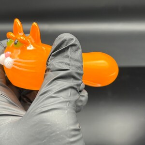 以下が含まれることがあります： 緑色の目で白いひげのあるオレンジ色のガラス製の猫のパイプ
