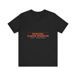 May include: A black short-sleeved t-shirt featuring orange text that reads PRINCIPAL CLAUDE OPERATOR, with a horizontal line above it and the smaller text Level IV · Anthropic Adjacent printed in white below the main orange lettering.