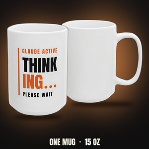 May include: Two white ceramic mugs with a 15 oz capacity. One mug features the orange and black text CLAUDE ACTIVE THINK ING... PLEASE WAIT with a vertical orange line. The other mug is plain white with a handle on the right side.