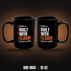 May include: Two black ceramic mugs featuring the white and orange text CLAUDE AI BUILT WITH CLAUDE FUELED BY COFFEE. The mugs have a handle on the side and the text ONE MUG 15 OZ is printed below them, indicating the capacity of the drinkware.