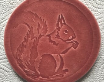 Handmade round tile,  'Red Squirrel' design in claret colour glaze, made in UK