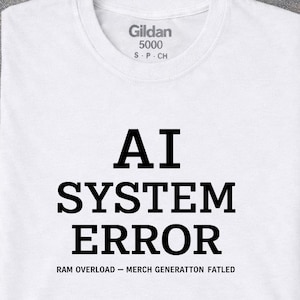 Puede incluir: Una camiseta blanca de manga corta con el texto negro AI SYSTEM ERROR en una fuente negrita y centrada. Debajo, un texto más pequeño dice RAM OVERLOAD - MERCH GENERATTON FATLED. La camiseta incluye una etiqueta Gildan 5000 en el cuello.
