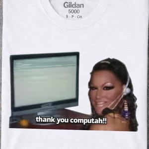 May include: A white t-shirt featuring a graphic print of a person wearing a headset in front of a computer monitor. The text below the monitor reads, "thank you computah!!". The shirt has a Gildan 5000 brand label printed on the inside neck area.