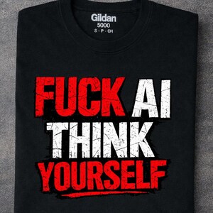 Puede incluir: Una camiseta negra de manga corta con un estampado gráfico desgastado con el texto FUCK AI en rojo y blanco, y THINK YOURSELF en blanco y rojo. La camiseta tiene una etiqueta Gildan 5000 impresa en el interior de la zona del cuello.
