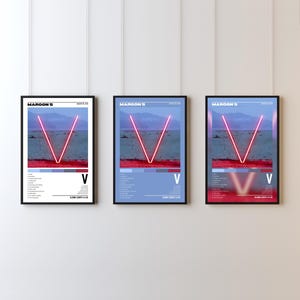 May include: Three framed posters featuring the Maroon 5 album "V". Each poster has a black frame and a design with a red "V" over a landscape. The album title and tracklist are visible on the posters.