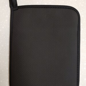 May include: Black pot holder with a hanging loop. The pot holder is made of a textured fabric.