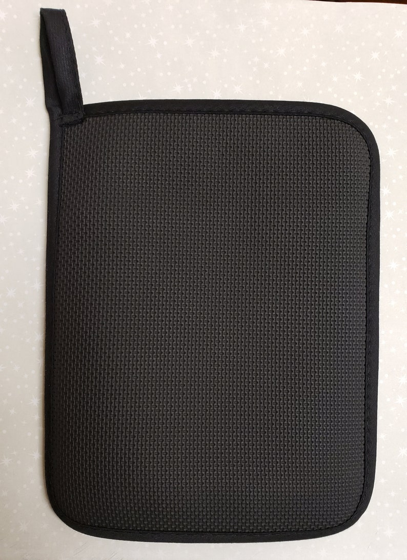 May include: Black pot holder with a hanging loop. The pot holder is made of a textured fabric.