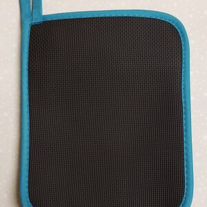 May include: Black pot holder with a teal blue border. The pot holder has a textured surface and a hanging loop.