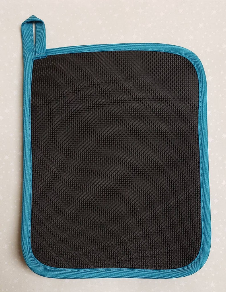 May include: Black pot holder with a teal blue border. The pot holder has a textured surface and a hanging loop.