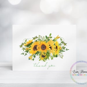 May include: A white card featuring a watercolor illustration of sunflowers with green leaves and stems. The words "thank you" are written in green script below the flowers. A colorful circular logo is in the bottom right corner.