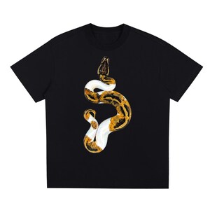 May include: Black t-shirt featuring a detailed illustration of a snake. The snake is depicted with a pattern of brown, white, and yellow scales. The snake is coiled in a vertical position, with its head at the top of the shirt.