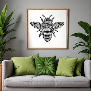 Peut inclure: Illustration d'abeille noire et blanche encadrée, au-dessus d'un canapé gris avec des coussins verts. Le dessin de l'abeille présente des lignes détaillées. Des plantes en pot encadrent le canapé.