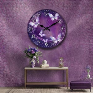 May include: A round wall clock with a purple face featuring white butterflies and black hands. The clock is set against a textured purple wall. The scene includes a table with a vase of flowers, a decorative item, and an hourglass.