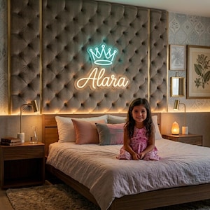 Puede incluir: Dormitorio con cabecero acolchado con un letrero de neón que dice "Alara" con una corona. Una niña con un vestido rosa está sentada en la cama. La habitación tiene mesitas de noche y lámparas de madera.