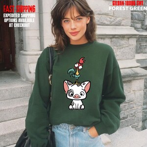 May include: Forest green sweatshirt featuring a cartoon illustration of a rooster standing on top of a pig. The sweatshirt has the text "GILDAN 18000 SWT FOREST GREEN" printed on it. The image also includes the text "FAST SHIPPING EXPEDITED SHIPPING OPTIONS AVAILABLE AT CHECKOUT".