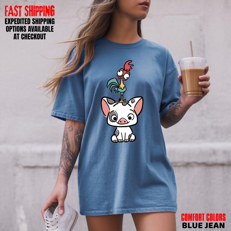 May include: Blue jean colored t-shirt featuring a cartoon pig with a rooster on its head. The shirt has the text "COMFORT COLORS BLUE JEAN" in the bottom right corner. The top left corner has the text "FAST SHIPPING EXPEDITED SHIPPING OPTIONS AVAILABLE AT CHECKOUT".