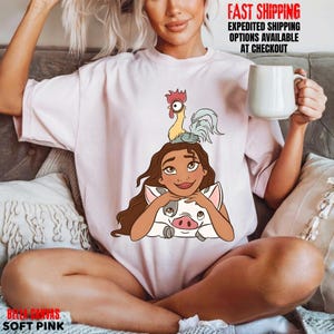 May include: Soft pink Bella + Canvas t-shirt with a cartoon illustration of a character, a pig, and a rooster. The shirt has the words "FAST SHIPPING" and "EXPEDITED SHIPPING OPTIONS AVAILABLE AT CHECKOUT" printed on it.