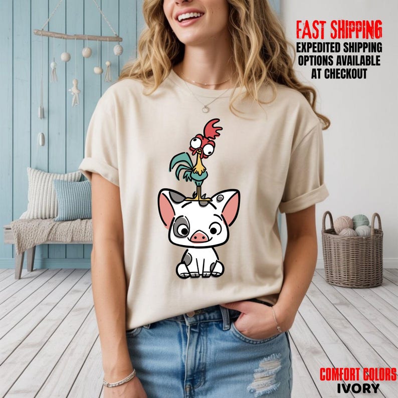 May include: Ivory-colored t-shirt featuring a cartoon illustration of a pig with a rooster on its head. The pig is white with black spots and pink ears. The rooster is red, green, and yellow. Text on the shirt reads "FAST SHIPPING" and "COMFORT COLORS IVORY".