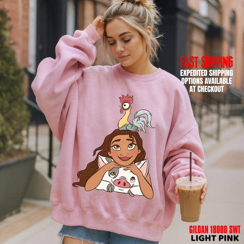 May include: Pale pink sweatshirt with a cartoon illustration of a character with a pig and rooster. The sweatshirt has long sleeves and a crew neck. The text "GILDAN 18000 SWT LIGHT PINK" is printed at the bottom.