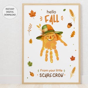 May include: A digital art print in a wooden frame featuring a handprint scarecrow with a green and orange hat. The text reads hello FALL and From your little SCARECROW, surrounded by illustrations of autumn leaves, wheat stalks, and acorns.