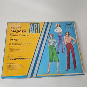 Op de afbeelding: Een vintage AFI Magic-Fit patroon voor broeken. De doos bevat illustraties van vrouwen in verschillende broekstijlen. De doos is geel en blauw met de tekst "The New Magic-Fit Master Pattern for PANTS".