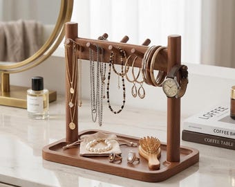 May include: A wooden jewelry organizer with a tray base and vertical posts. Various necklaces, bracelets, earrings, and a watch are displayed. A small bag, rings, and a brush are also on the tray. The organizer is on a white surface.