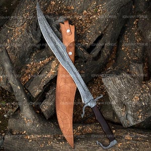 May include: A large, curved sword with an ornate, patterned blade and a dark wooden handle. The sword is displayed with a brown leather sheath, resting on a pile of wood logs. The blade has a silver finish.