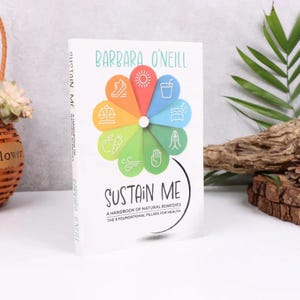 Może przedstawiać: Twarda oprawa książki zatytułowana "Sustain Me" autorstwa Barbary O'Neill. Okładka przedstawia kolorowy kwiatowy wz&oacute;r z ikonami i tekstem "A Handbook of Natural Remedies, The 9 Foundational Pillars for Health."