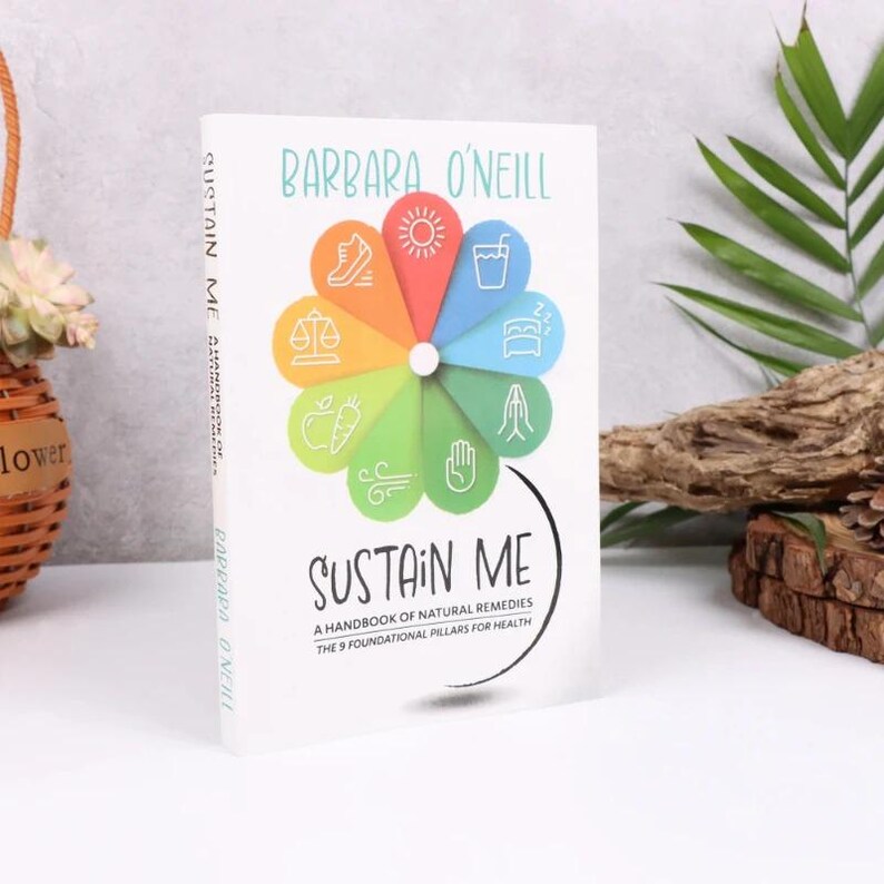 Może przedstawiać: Twarda oprawa książki zatytułowana "Sustain Me" autorstwa Barbary O'Neill. Okładka przedstawia kolorowy kwiatowy wz&oacute;r z ikonami i tekstem "A Handbook of Natural Remedies, The 9 Foundational Pillars for Health."