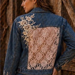 Könnte beinhalten: Jeansjacke mit floraler Stickerei auf Schultern und Ärmeln. Die Rückseite hat eine blassrosa Spitzenverkleidung. Die Jacke hat einen klassischen Kragen und einen Knopfverschluss. Die Jacke wird mit passenden Jeans kombiniert.