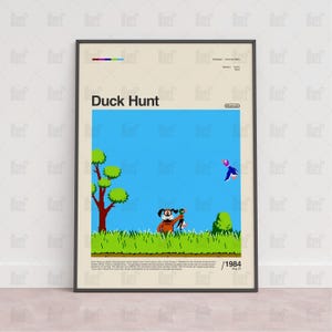 May include: Framed poster featuring the classic video game "Duck Hunt." The artwork depicts a pixelated scene with a dog, a duck, and a grassy field against a blue sky. The title "Duck Hunt" is prominently displayed.
