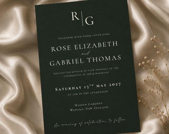 May include: A dark green rectangular wedding invitation card with white serif text. The card features the initials R and G, the names Rose Elizabeth and Gabriel Thomas, the date Saturday 13th May 2027, and the location Maison Gardens, Wanaka, New Zealand.