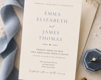May include: A cream-colored wedding invitation card with blue text reading Emma Elizabeth and James Thomas, Twenty-First of May Two Thousand Twenty-Seven, The Manor House, Queenstown, New Zealand, and Celebrate with us into the evening.