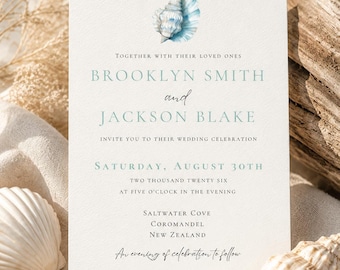 May include: A rectangular wedding invitation card featuring a watercolor illustration of a blue seashell at the top. The text reads: Together with their loved ones, Brooklyn Smith and Jackson Blake, invite you to their wedding celebration, Saturday, August 30th, two thousand twenty six, at five o'clock in the evening, Saltwater Cove, Coromandel, New Zealand, an evening of celebration to follow.
