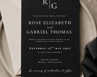 May include: A black rectangular wedding invitation card with white serif and script text. The card features the initials R and G separated by a vertical line, followed by the names Rose Elizabeth and Gabriel Thomas, date, and location details.
