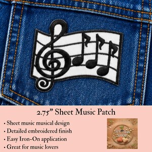 May include: An embroidered patch featuring a black treble clef and musical notes on a white background with black staff lines. The patch is attached to blue denim fabric. The text 2.75" Sheet Music Patch is visible below the image.