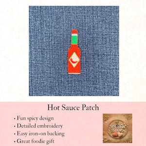 May include: An embroidered iron-on patch shaped like a hot sauce bottle with a red body, a green cap, and a white diamond-shaped label featuring a small red chili pepper graphic, centered on a textured blue denim fabric background.