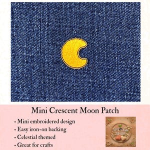 May include: A small, yellow embroidered crescent moon patch centered on a dark blue denim fabric background. The patch features a dense, textured stitch pattern in a bright yellow thread, creating a distinct moon shape against the textured denim.