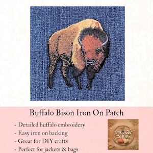 May include: Embroidered buffalo bison iron-on patch. The patch features a detailed design of a bison in shades of brown, black, and orange, set against a blue denim background. The text "Buffalo Bison Iron On Patch" is visible.