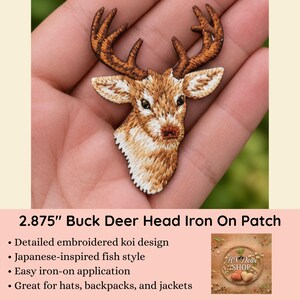 May include: An iron-on patch shaped like a buck deer head with detailed brown and white embroidery. The patch measures 2.875 inches in height and features a realistic depiction of a deer with prominent antlers, pointed ears, and textured fur.
