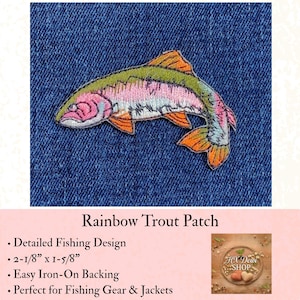 May include: An embroidered iron-on patch shaped like a rainbow trout fish. The patch features a green back, a pink lateral stripe, and orange fins, measuring 2-1/8 inches by 1-5/8 inches. It is displayed against a dark blue denim fabric background.