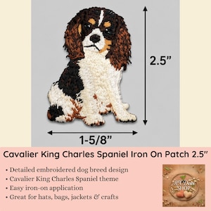 May include: An embroidered iron-on patch featuring a Cavalier King Charles Spaniel dog with black, white, and brown fur. The patch measures 2.5 inches in height and 1-5/8 inches in width, as indicated by the black measurement arrows in the image.