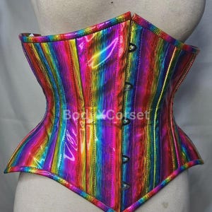 May include: A vibrant, rainbow-striped corset with a glossy finish. The corset has a traditional shape, with a pointed lower edge and a curved upper edge. It features black fasteners down the front. The measurements are in centimeters.