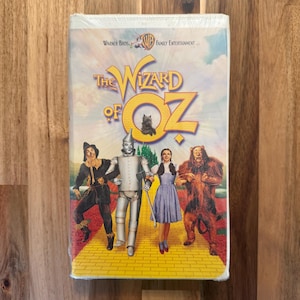 May include: A VHS tape of "The Wizard of Oz" featuring the film's title in yellow and the characters: Scarecrow, Tin Man, Dorothy, and the Cowardly Lion. The Warner Bros. Family Entertainment logo is visible.