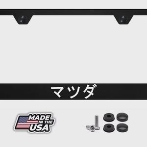 May include: Black license plate frame with the Japanese word "マツダ" in white. Includes mounting hardware and a "Made in the USA" sticker. The frame is rectangular with rounded corners.