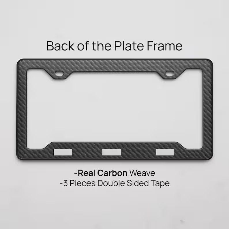 May include: A black carbon fiber license plate frame with a woven texture. The frame has a rectangular shape with rounded corners and three rectangular cutouts at the bottom. Text on the image reads "Back of the Plate Frame", "-Real Carbon Weave", and "-3 Pieces Double Sided Tape".