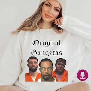 Puede incluir: Sudadera blanca con el texto "Original Gangstas" en fuente gótica. Debajo del texto, tres caras de hombres. Los hombres llevan monos naranjas. La sudadera es de cuello redondo y manga larga.