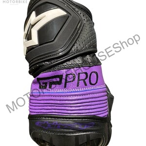 Puede incluir: Guante de moto negro y morado con detalles blancos. El guante presenta el texto "GP PRO" en blanco sobre una banda morada. La parte superior tiene un panel protector negro con un dise&ntilde;o de "M" blanco. Se ve cuero perforado.