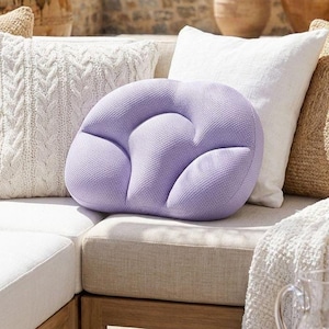 Peut inclure: Un coussin de couleur lavande, de forme unique, avec une surface texturée. Le coussin est entouré d'autres coussins dans des tons de blanc et de beige, créant une atmosphère chaleureuse et accueillante. Le design du coussin est à la fois décoratif et fonctionnel, adapté à la décoration intérieure.